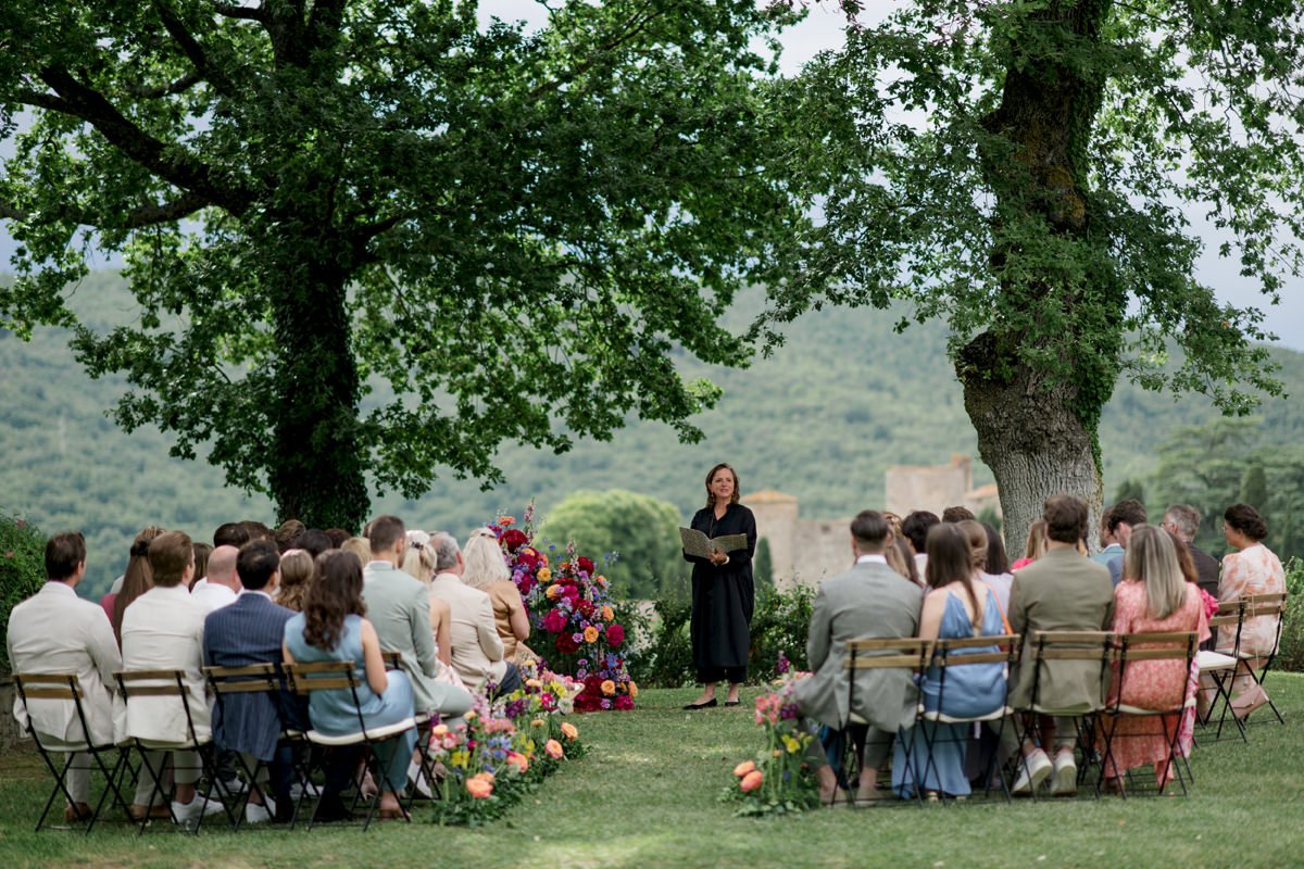 Wedding ceremony at Castello di Meleto with guests seated and the celebrant officiating, set against the Chianti countryside in Tuscany.