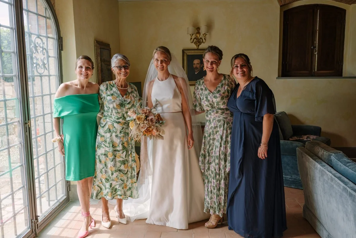 Bride with her mother and bridesmaids holding bouquets during preparations inside Le Filigare wedding venue.