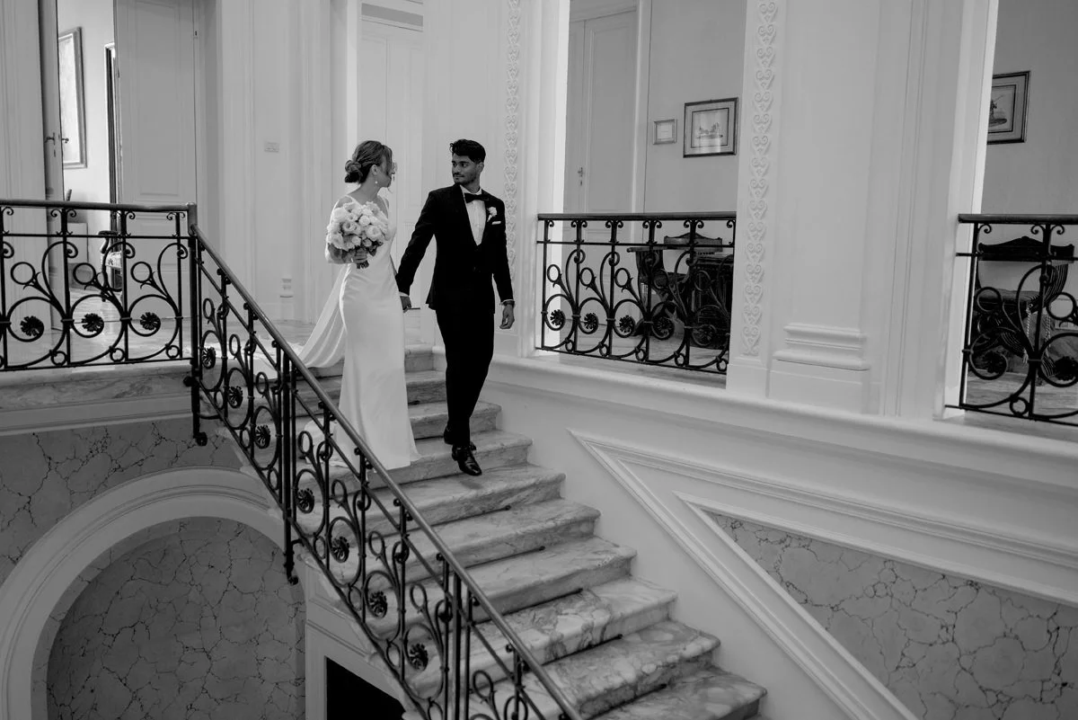 Black and white photo of the couple walking down the grand interior stairs at Tenuta di Monaciano.