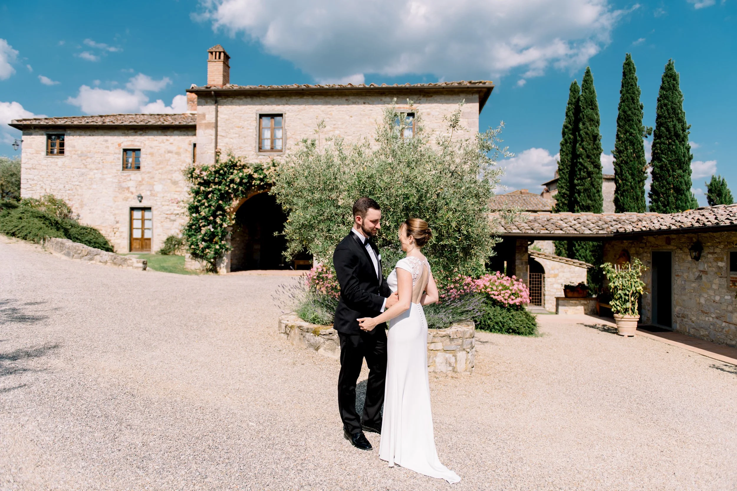 Couple holding hands during their first look in front of Castello di Spaltenna, surrounded by garden and historic property.