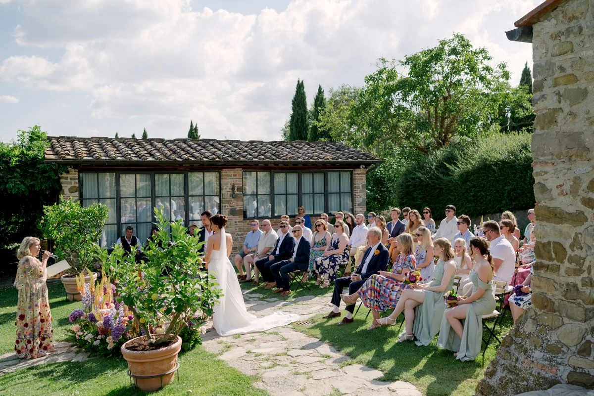 Wedding ceremony at Casa Cornacchi with guests seated and the lemon house visible behind the couple in Tuscany
