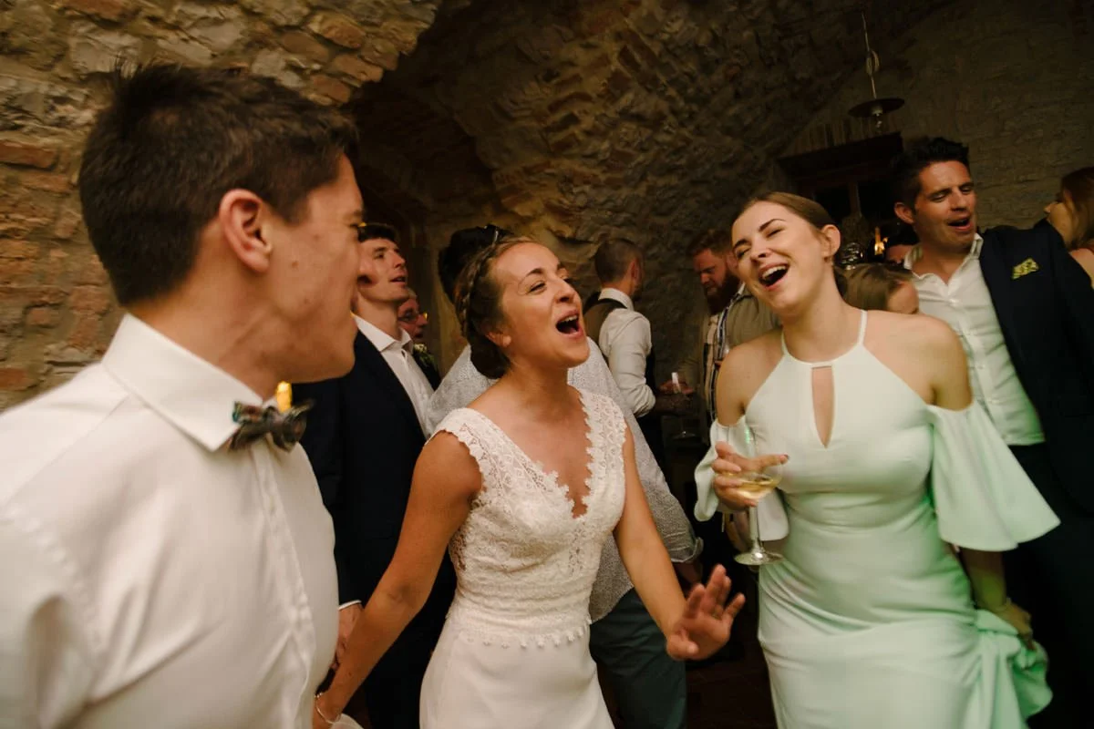 Bride and bridesmaid singing together during the wedding party celebration at Borgo Pietrafitta.