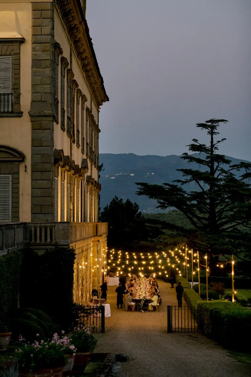 Evening wedding dinner next to the villa at Torre a Cona, illuminated by string lights in Tuscany.