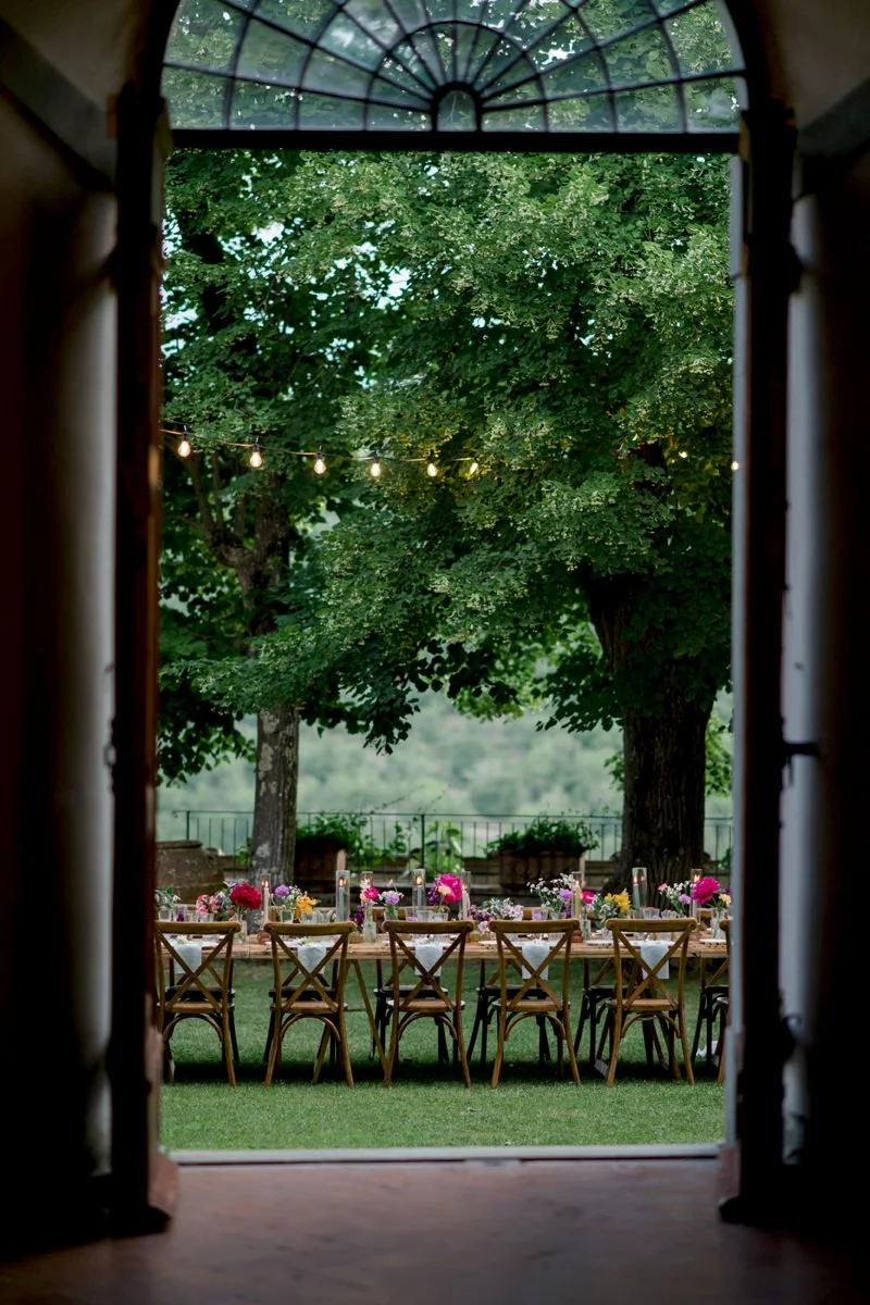 View of the wedding dinner table through the open castle doors at Castello di Meleto, capturing the atmosphere of the celebration in Tuscany.