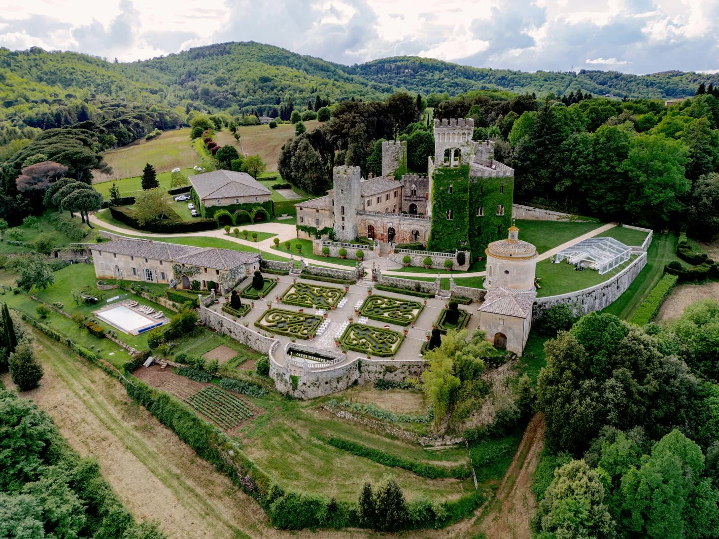 Wide view of Castello di Celsa in Tuscany, showing the hilltop castle and surrounding gardens in natural light.