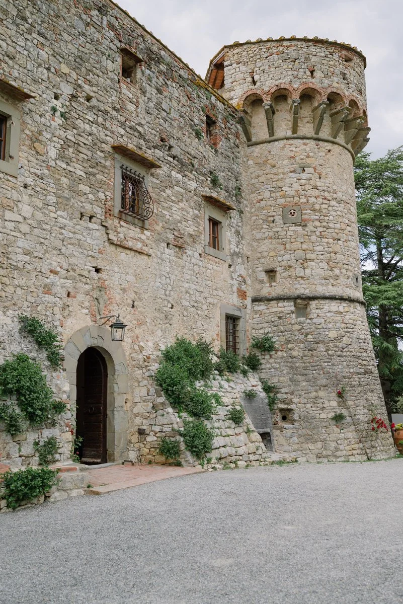 Architectural detail of the castle tower at Castello di Meleto, highlighting historic stonework against the Tuscan sky.