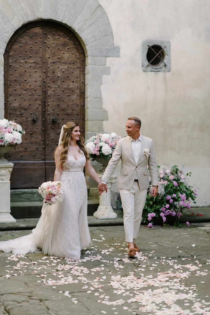 Couple walking from the ceremony in the courtyard of Castello del Trebbio.