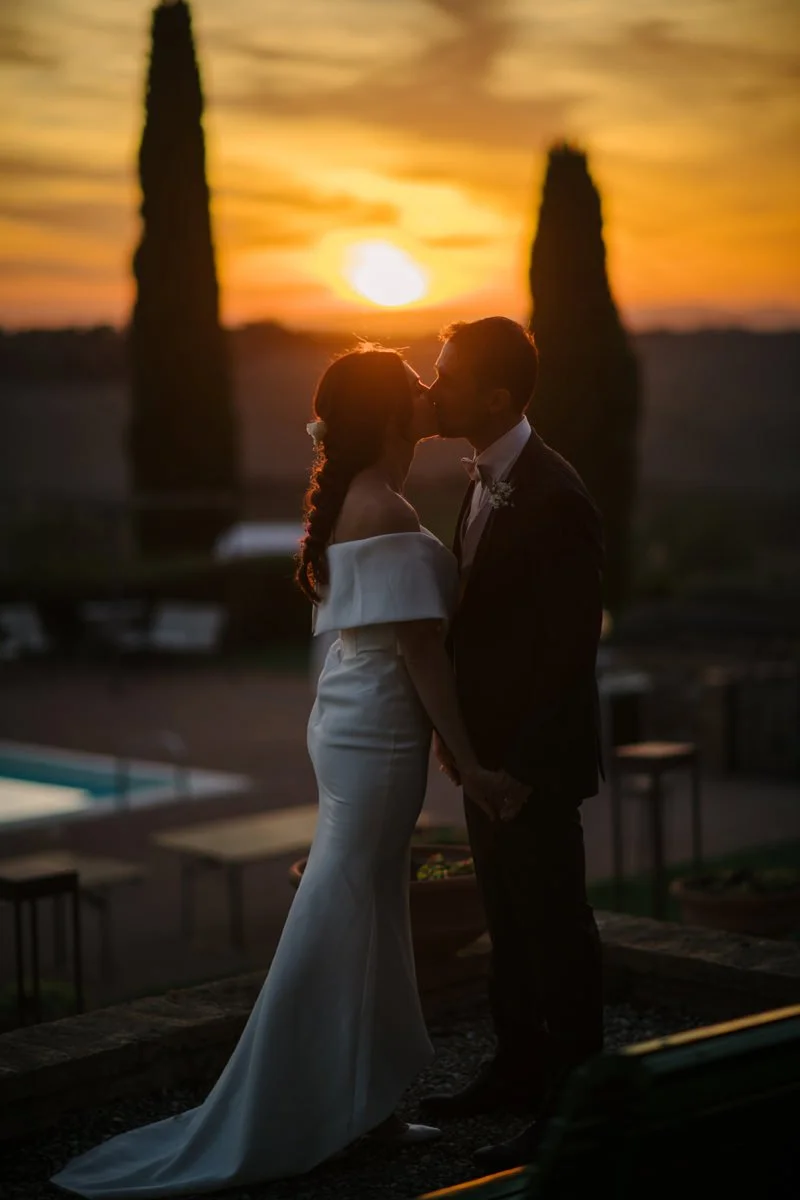 Bride and groom kissing during golden hour at Villa Boscarello with warm Tuscan sunset light.