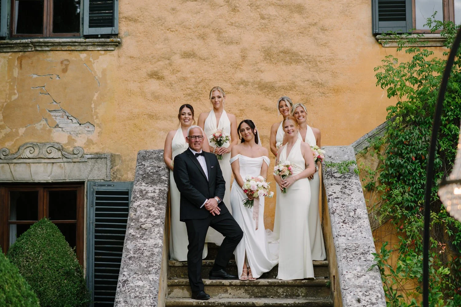 Bride with her father and bridesmaids gathered at the villa wall before the ceremony, Villa di Ulignano wedding