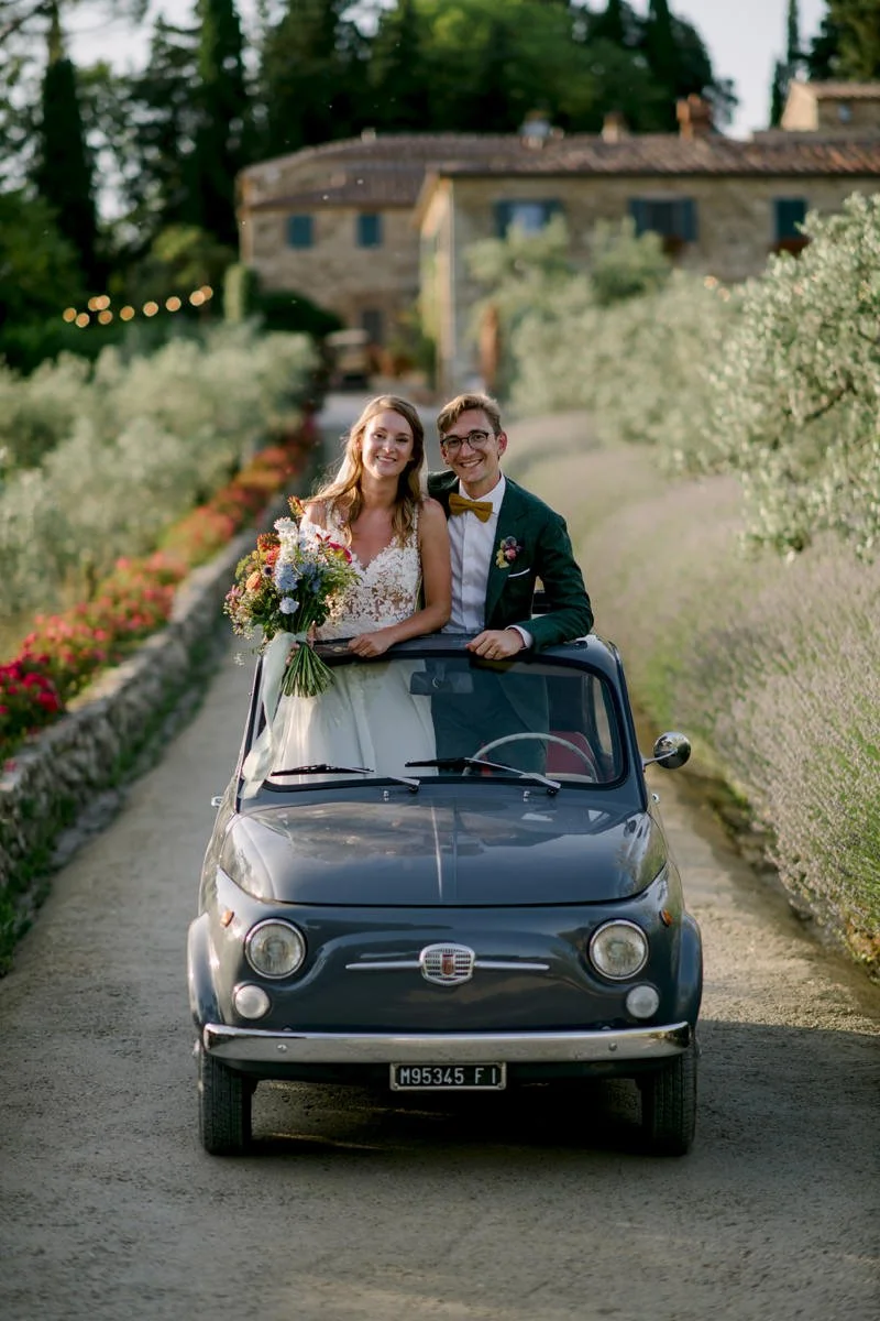 Bride and groom smiling while sitting in a Fiat 500 cabrio at Le Filigare wedding venue in Tuscany.