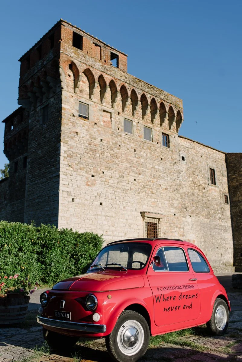 Classic Fiat 500 parked in front of Castello del Trebbio during a Tuscany wedding celebration.