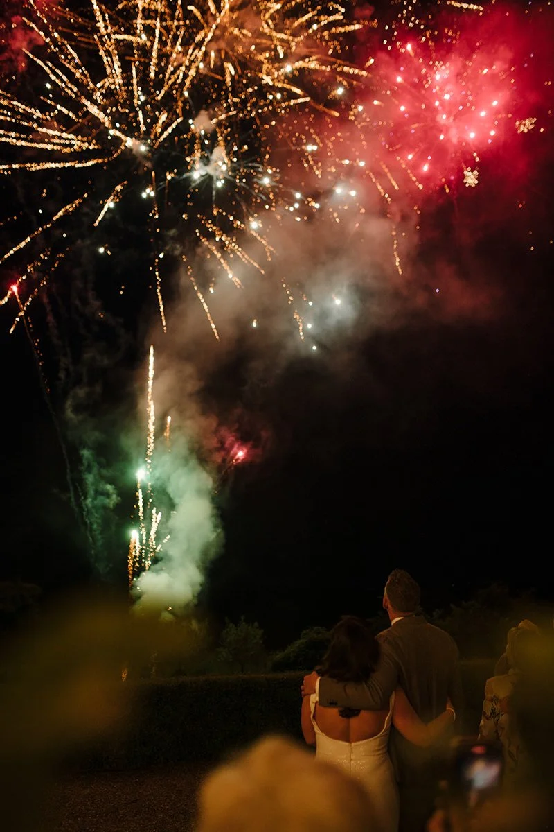 Bride and groom watching red fireworks together during their wedding celebration at Villa Boscarello.