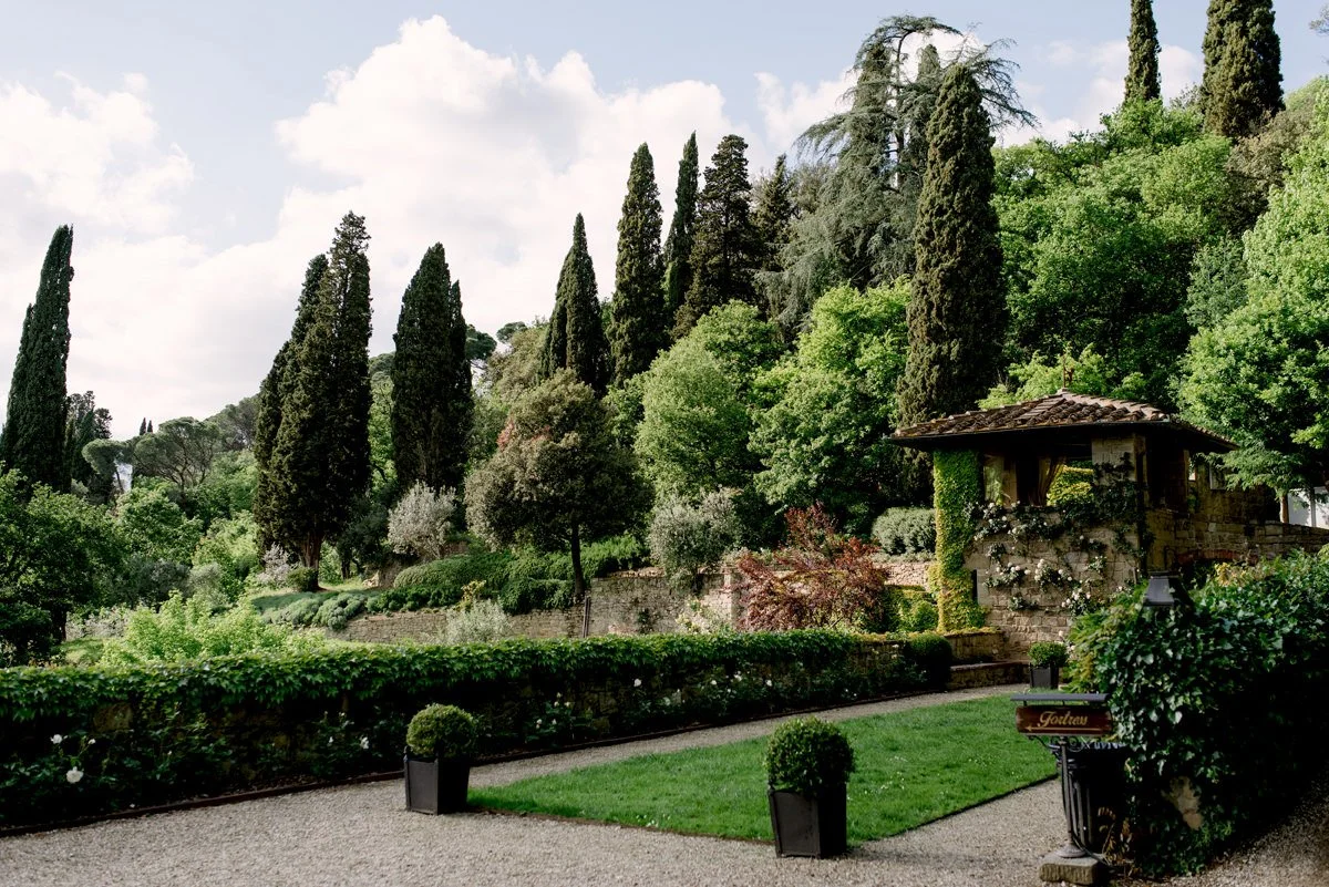 Formal garden at Villa Le Fontanelle wedding venue with tall Tuscan trees.