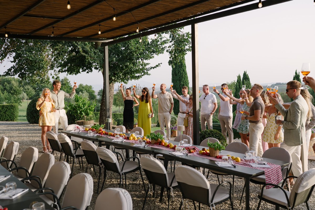 Bride and groom cheering with guests during a welcome pizza dinner at Villa Boscarello.