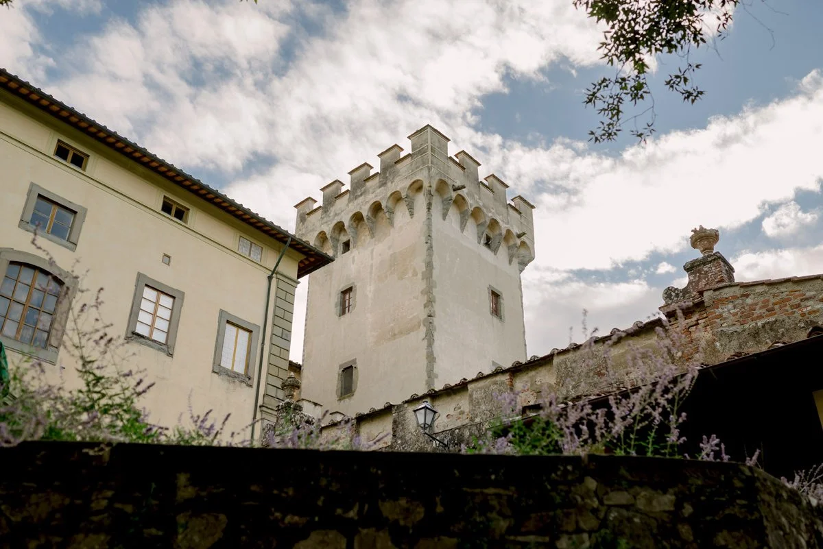 Historic tower of Torre a Cona rising above the estate, framed by dramatic clouds in the Tuscan sky.