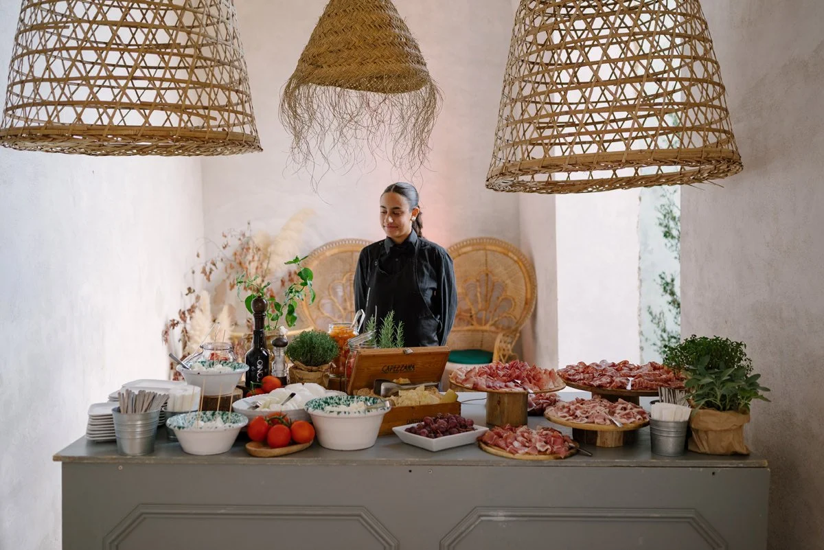 Aperitivo table filled with food set in a covered garden area at Torre a Cona during a Tuscany wedding.