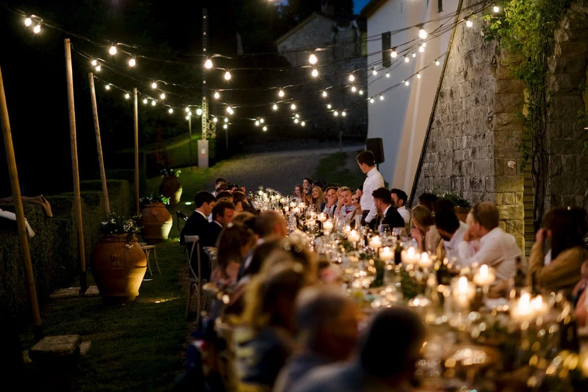 Wedding dinner at Borgo Pietrafitta with guests seated at long tables under string lights.
