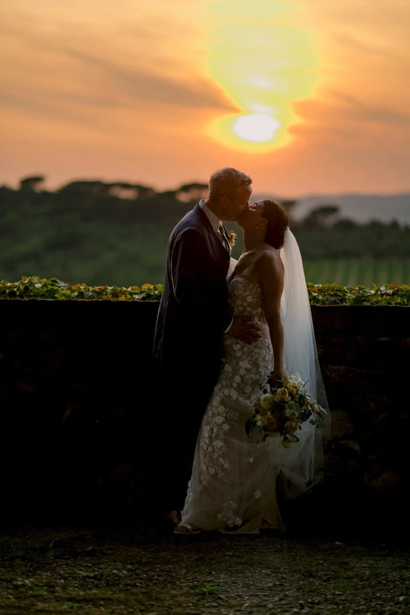Couple kissing on the terrace of Castello di Bossi during sunset with Tuscan countryside light.