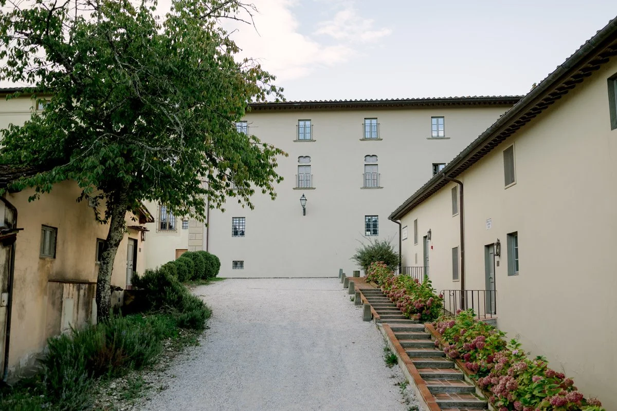 View of Torre a Cona villa with surrounding estate buildings set among the Tuscan countryside.