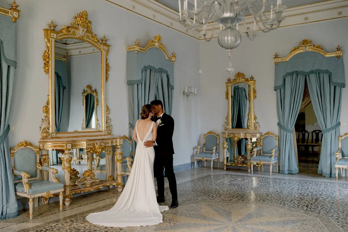 Bride and groom kissing inside the elegant ballroom at Tenuta di Monaciano wedding venue.