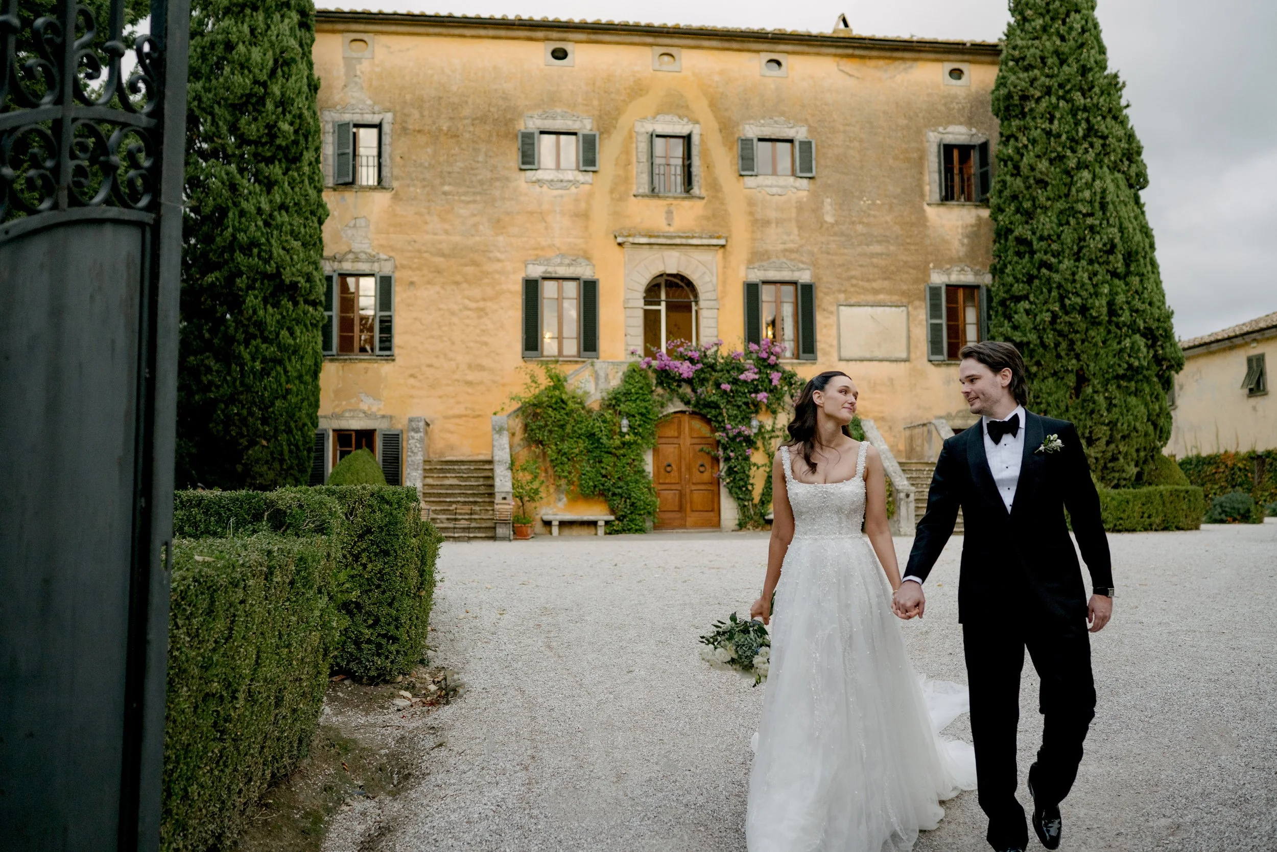 Real wedding photography at a Tuscany villa, showing a couple walking together after their ceremony in front of their wedding venue.