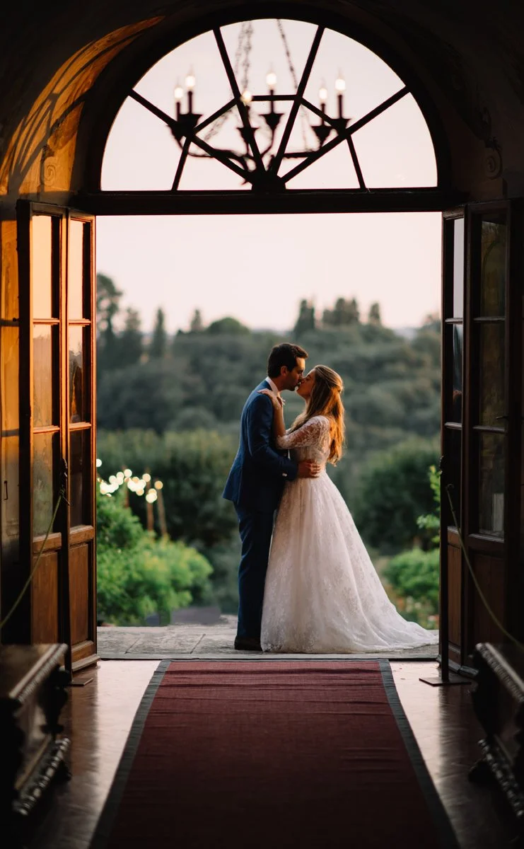 Wedding couple kissing at the entrance of Villa Medicea di Lilliano with garden view behind them