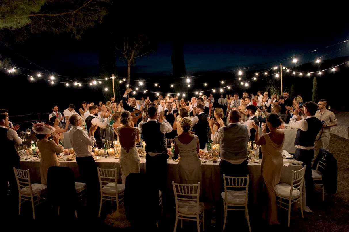 Wedding guests clapping and celebrating during dinner with live music at Conti di San Bonifacio.