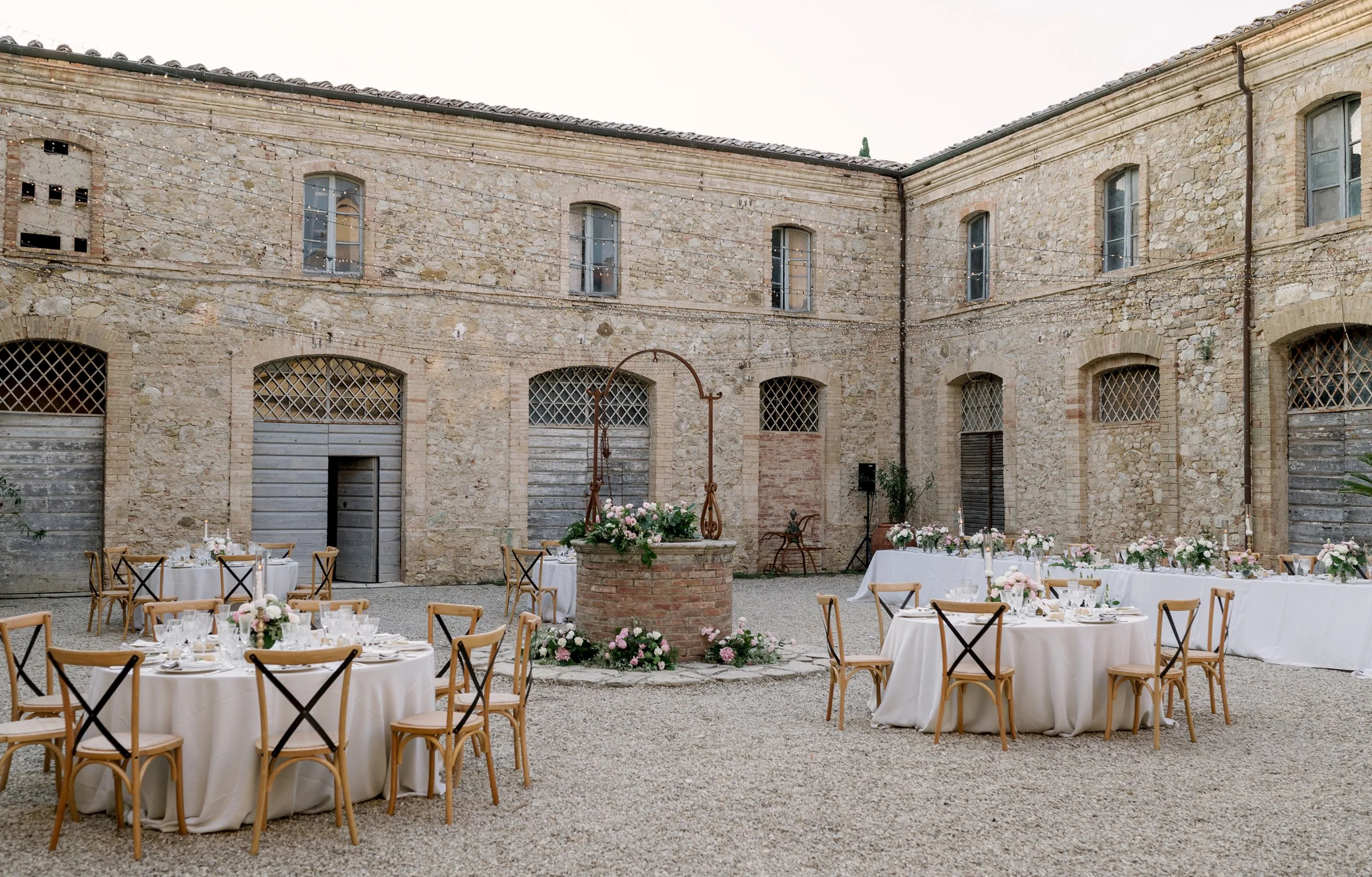 Wedding dinner setup in the courtyard of Tenuta di Monaciano with decorated tables and evening atmosphere.