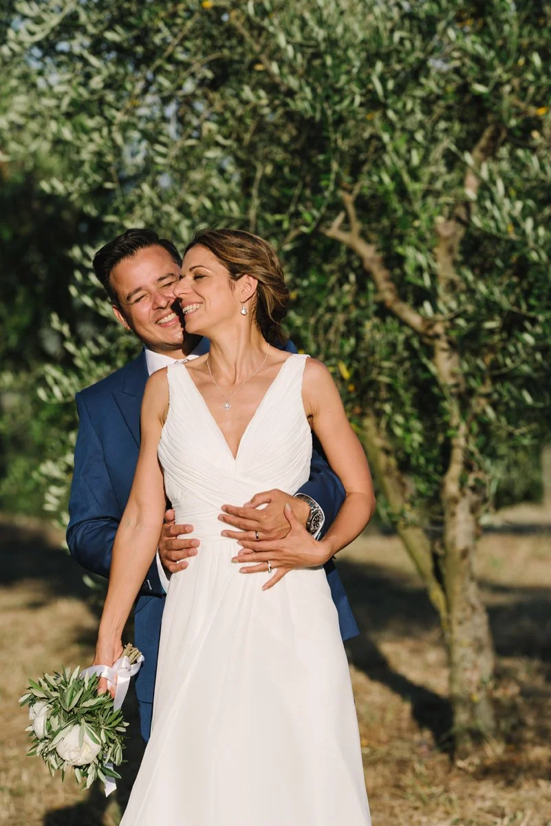 Wedding couple smiling closely together during a photoshoot in the olive grove at Villa Artimino in Tuscany.