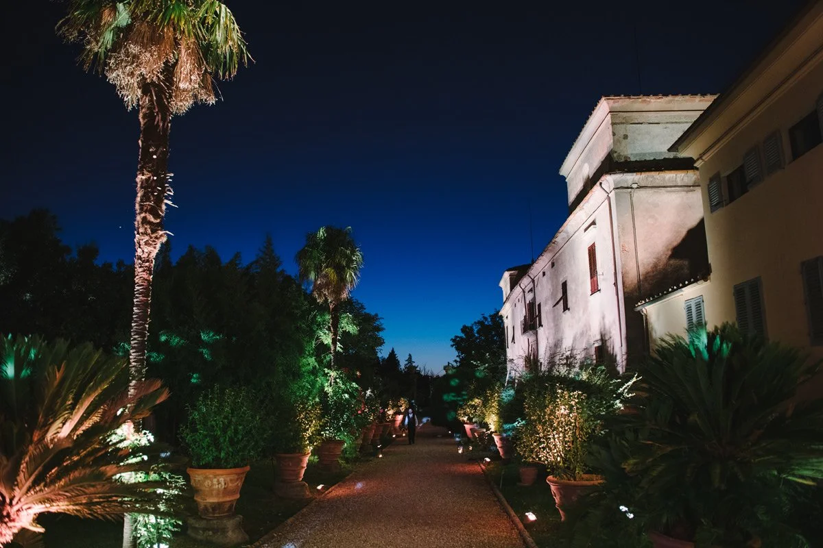 Small alley next to Villa Medicea di Lilliano at night with tall trees and soft lighting