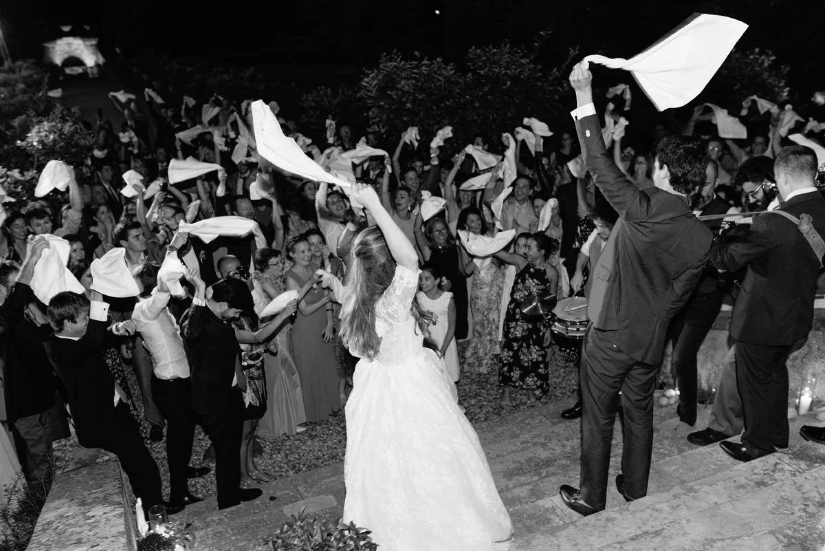 Black and white photo of wedding guests waving napkins during evening celebration at Villa Medicea di Lilliano