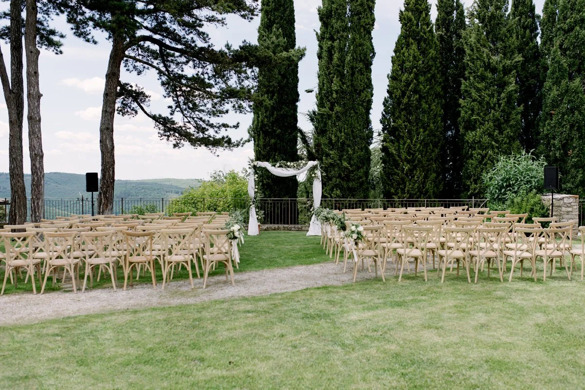 Outdoor wedding ceremony at Borgo Pietrafitta with a floral arch set on the garden terrace overlooking the Tuscan countryside.