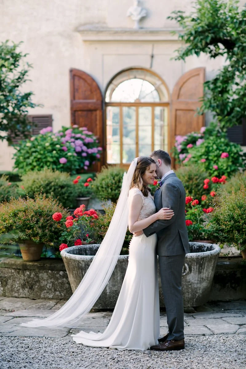 Wedding couple standing closely together in the courtyard of Villa Medicea di Lilliano