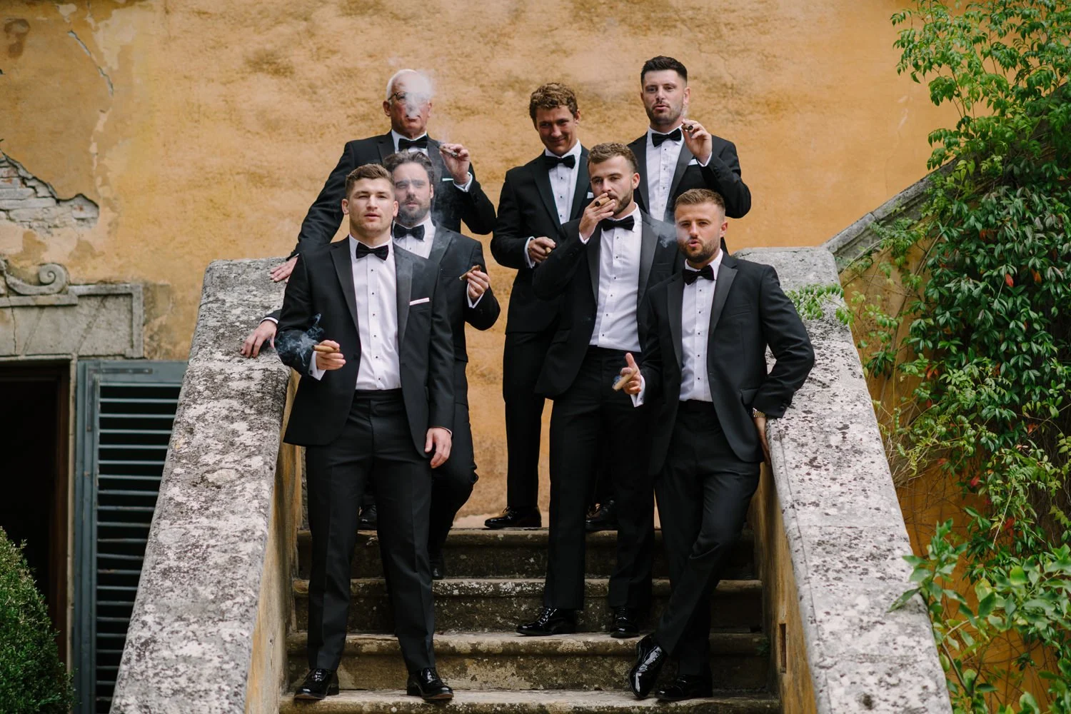 Groomsmen on the villa stairs sharing a cigar before the ceremony at Villa di Ulignano, FunkyBird Photography