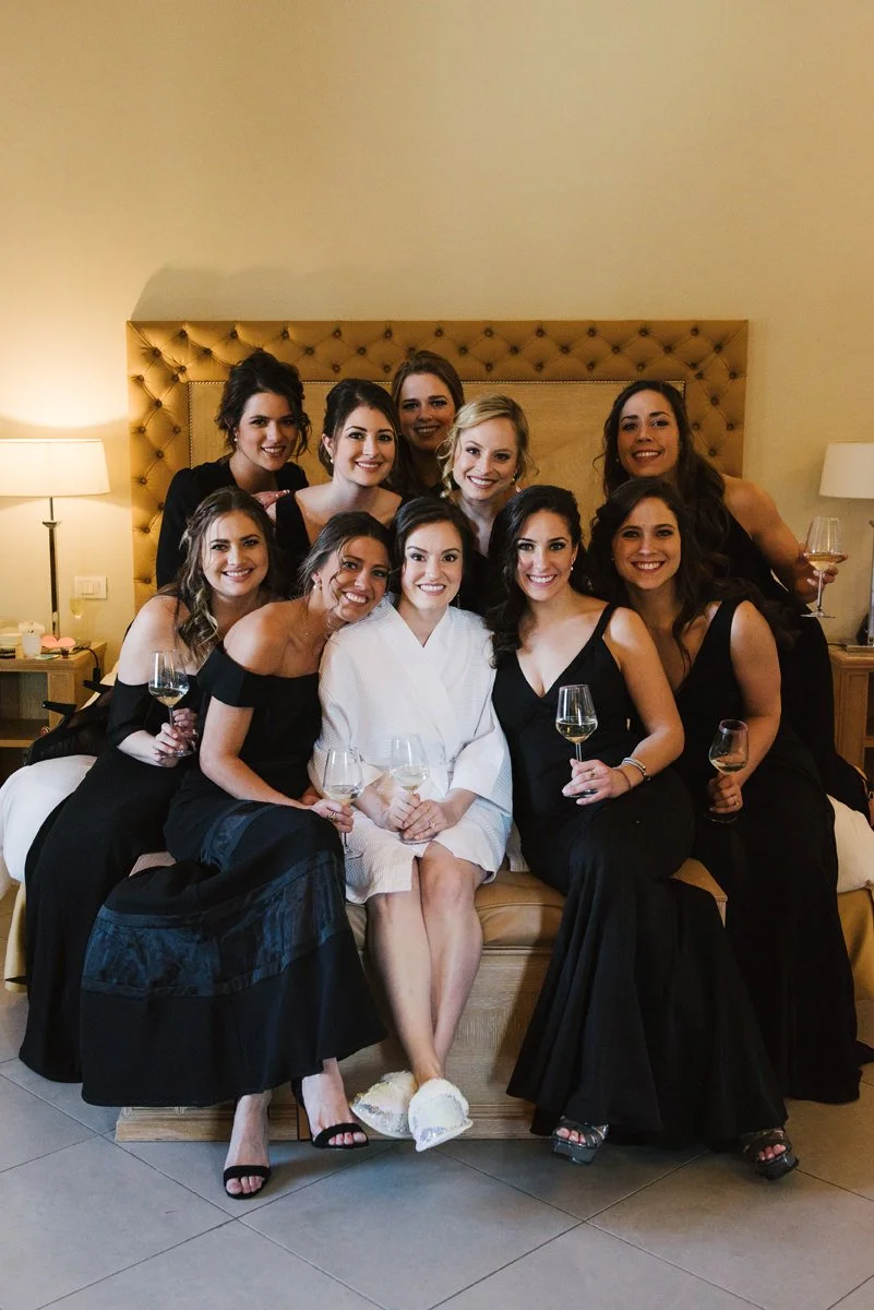 Bride sitting on the bed with her bridesmaids during wedding preparations at Villa Hotel Tolomei in Florence.