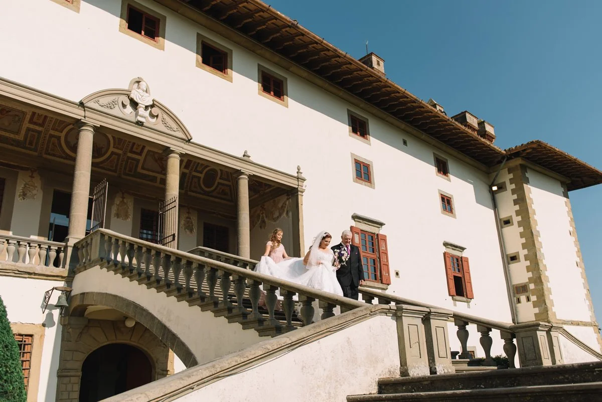 Bride and her father walking down the grand stairs of Villa Artimino toward the wedding ceremony.