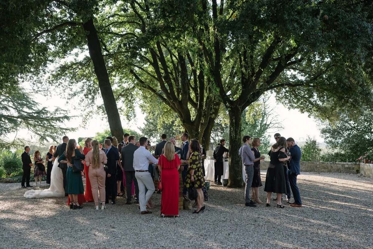 Wedding guests enjoying aperitivo together in the gardens of Castello Il Palagio wedding venue in Tuscany.
