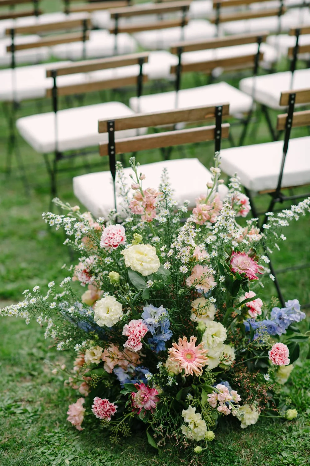 Ceremony floral installation in pink, peach and cornflower blue with the Volterra hills behind, Villa di Ulignano