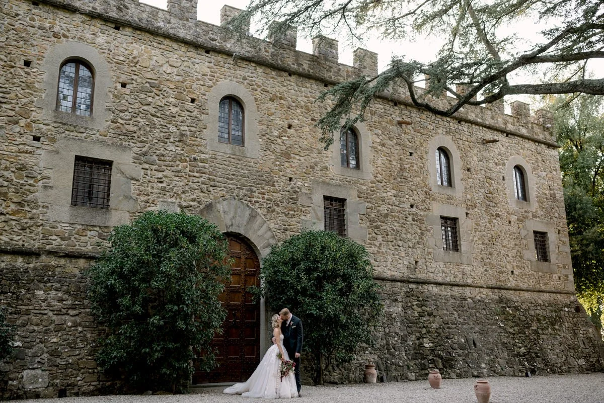 Bride and groom kissing in front of Castello Il Palagio.