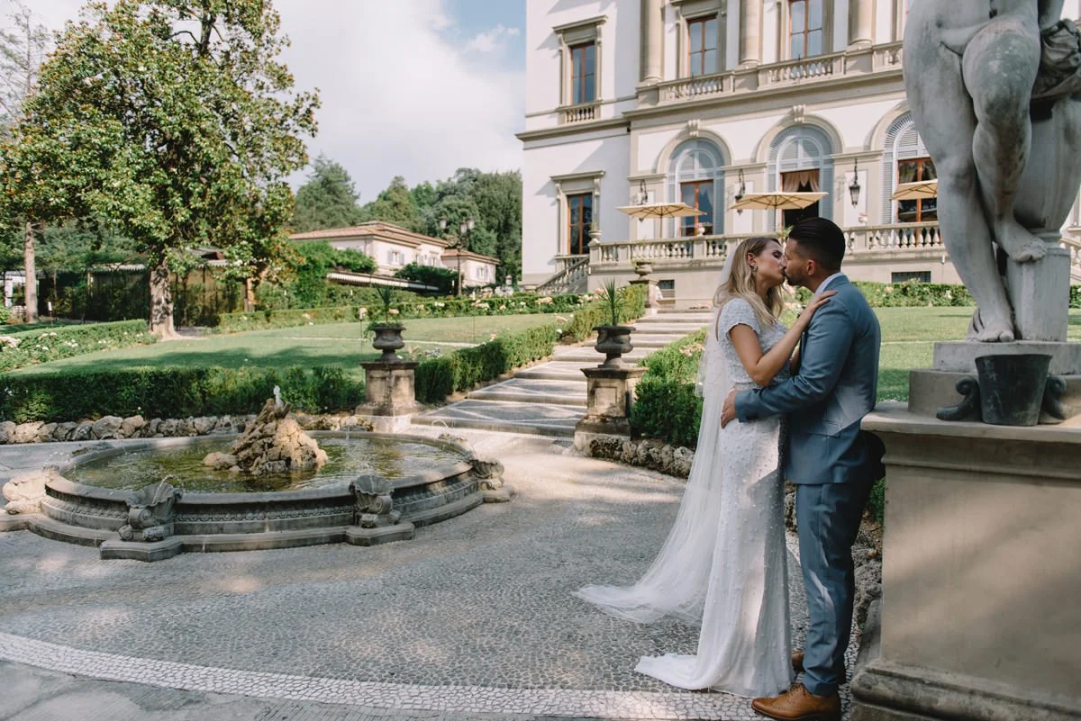 Couple kissing in front of the historic facade of Villa Cora in Florence.