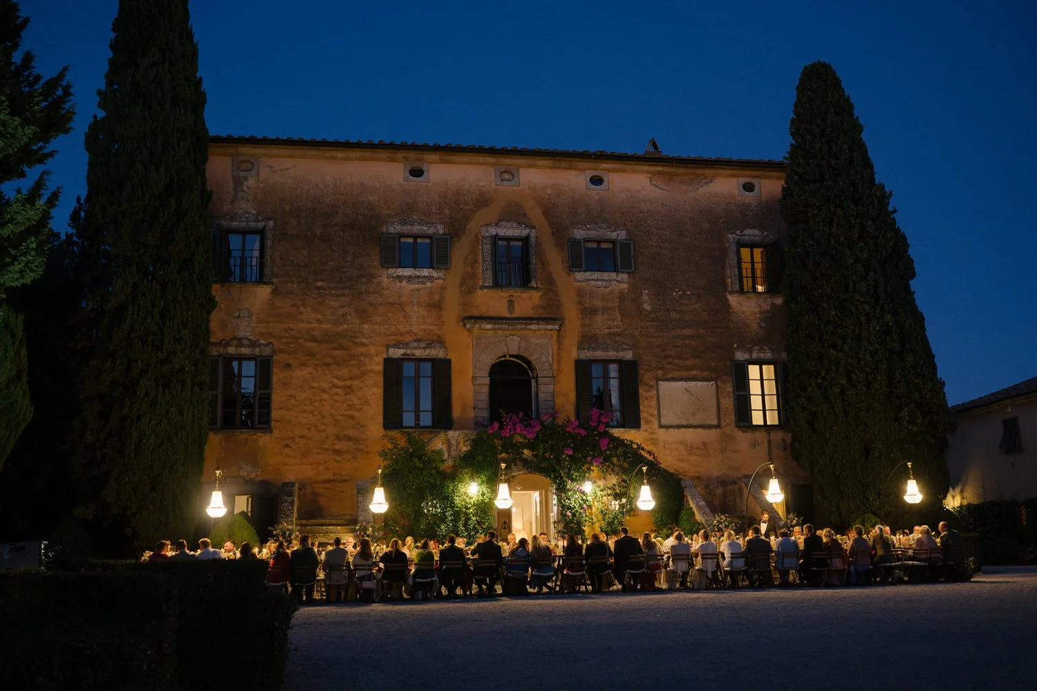 Wedding dinner in front of Villa di Ulignano at twilight with the full villa facade illuminated, FunkyBird Photography