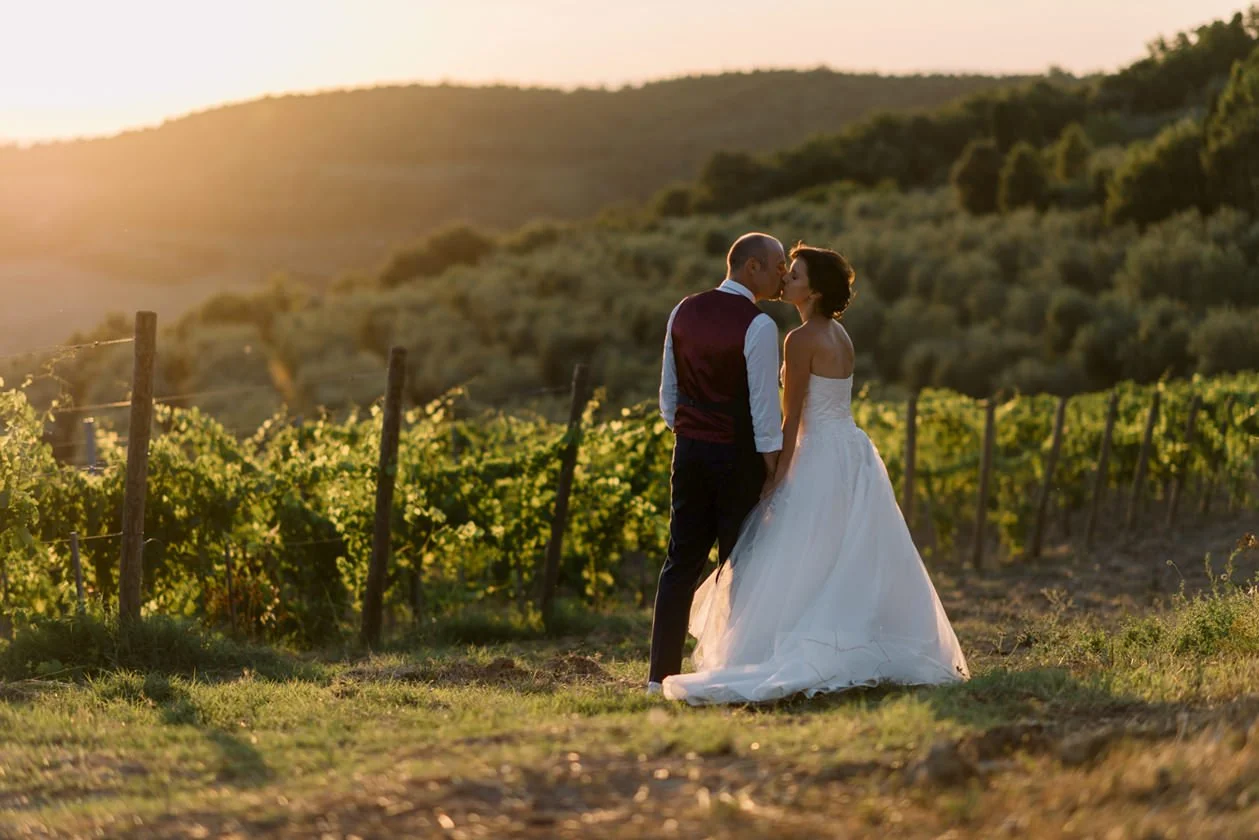 Couple kissing in the vineyards during golden hour at Terre di Nano wedding venue in Val d’Orcia.