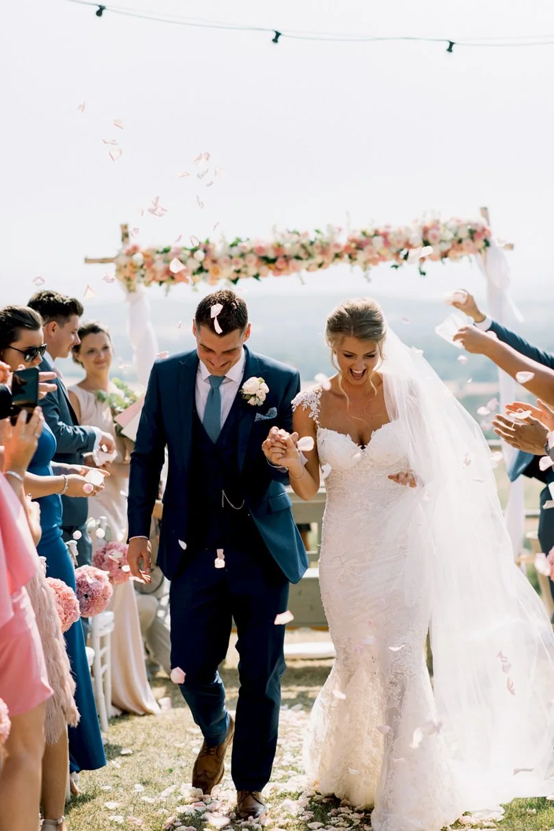 Just married couple walking after the ceremony while guests throw flower petals at Conti di San Bonifacio.