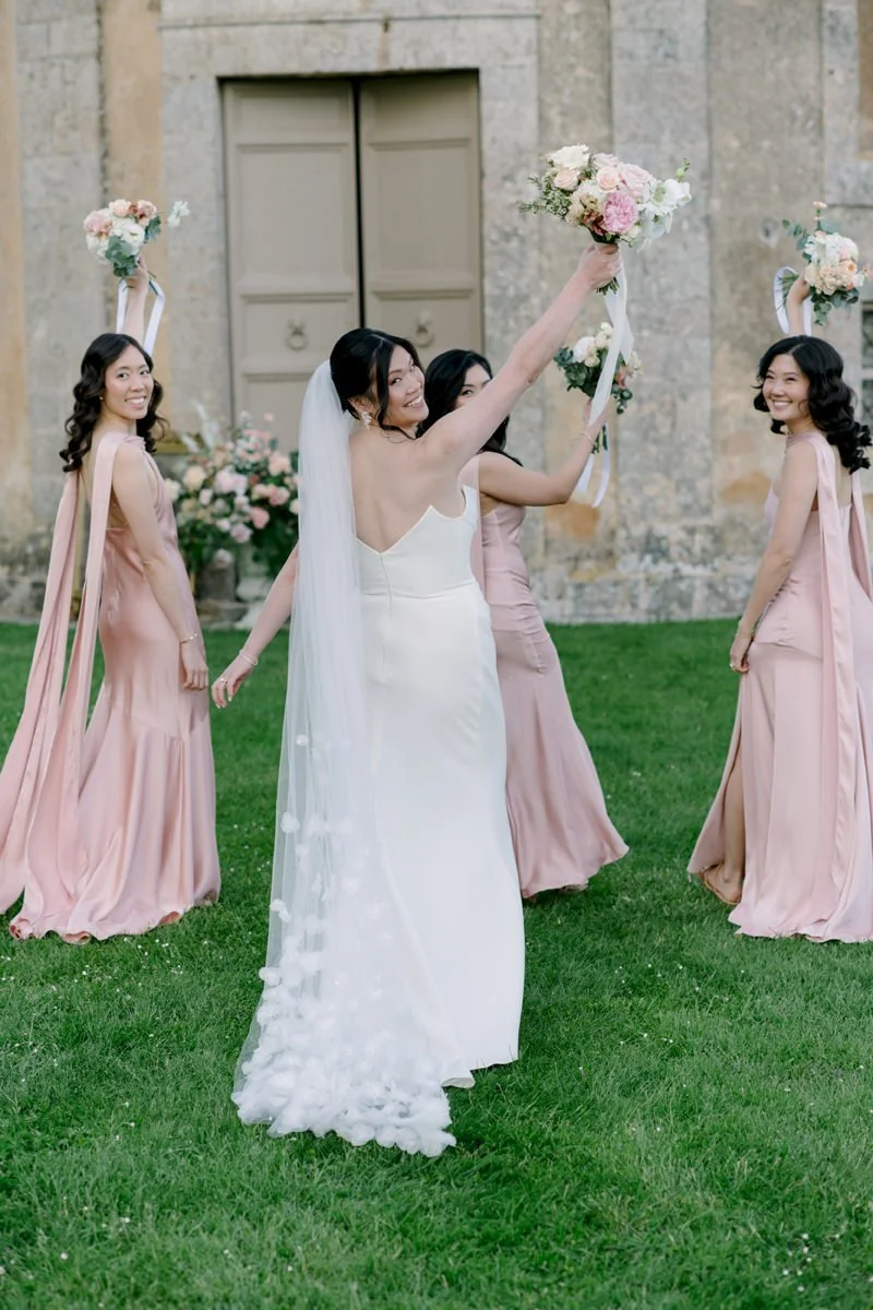 Bride and bridesmaids cheering with bouquets in the air, Castello di Celsa, Tuscany wedding photographer