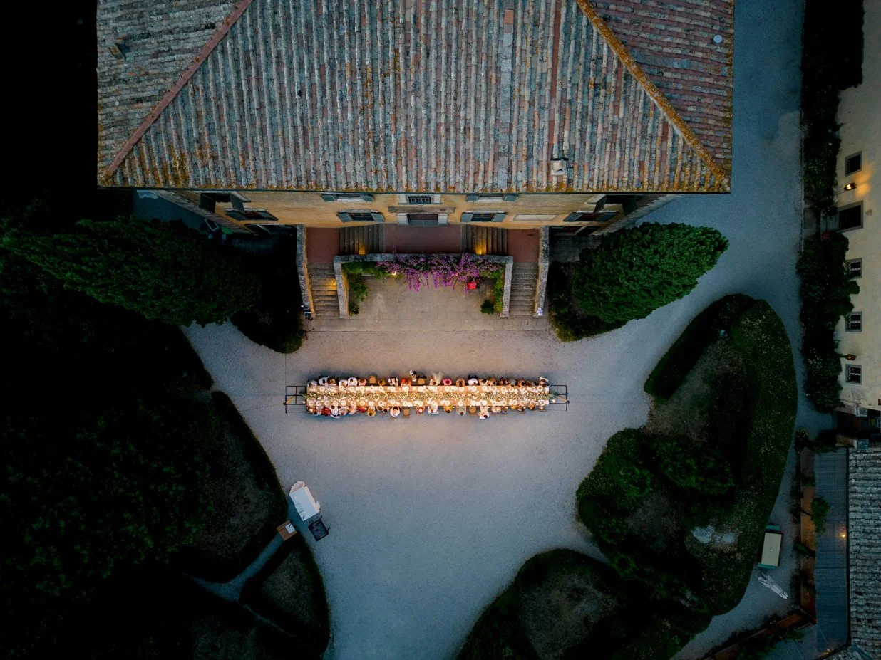 Drone view of a wedding dinner set in front of Villa di Ulignano, showing long tables arranged across the main outdoor space.
