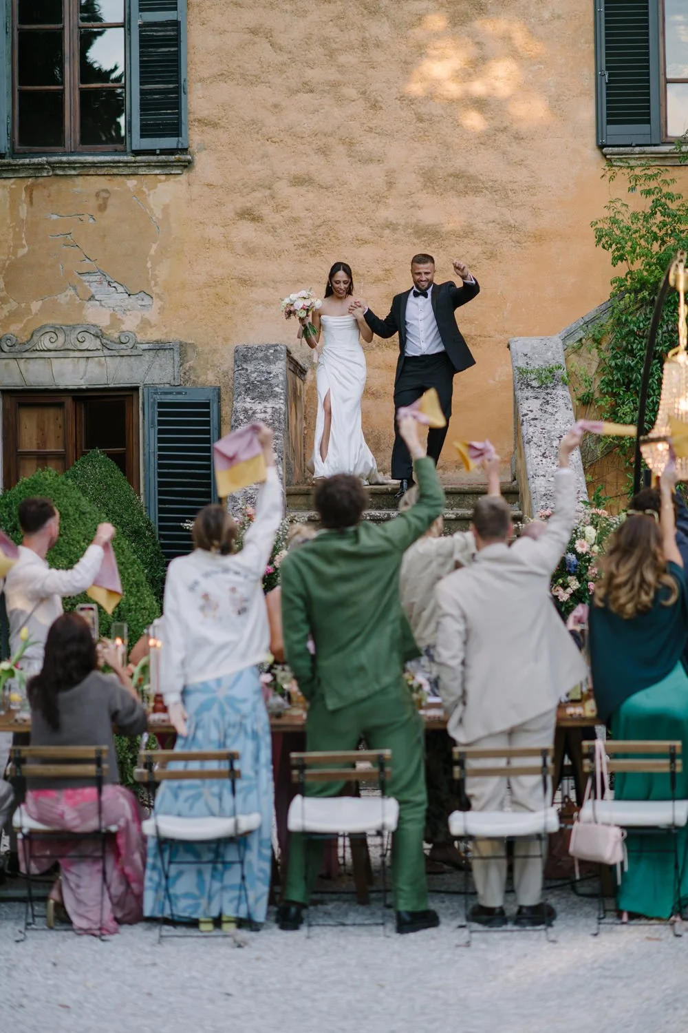 Amber and James walking back through the aisle with raised hands as guests throw petals at their Villa di Ulignano ceremony, October Tuscany wedding by FunkyBird Photography