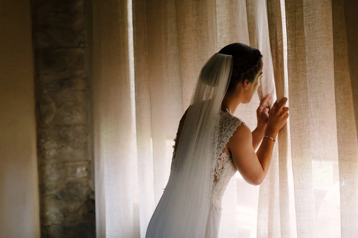 Bride looking through the window during wedding preparations at Borgo Pietrafitta.