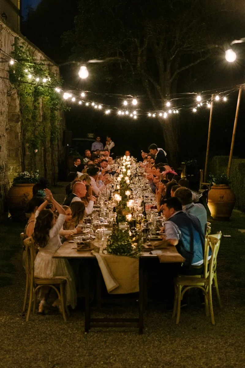Guests enjoying dinner together at Borgo Pietrafitta wedding reception under evening lights.