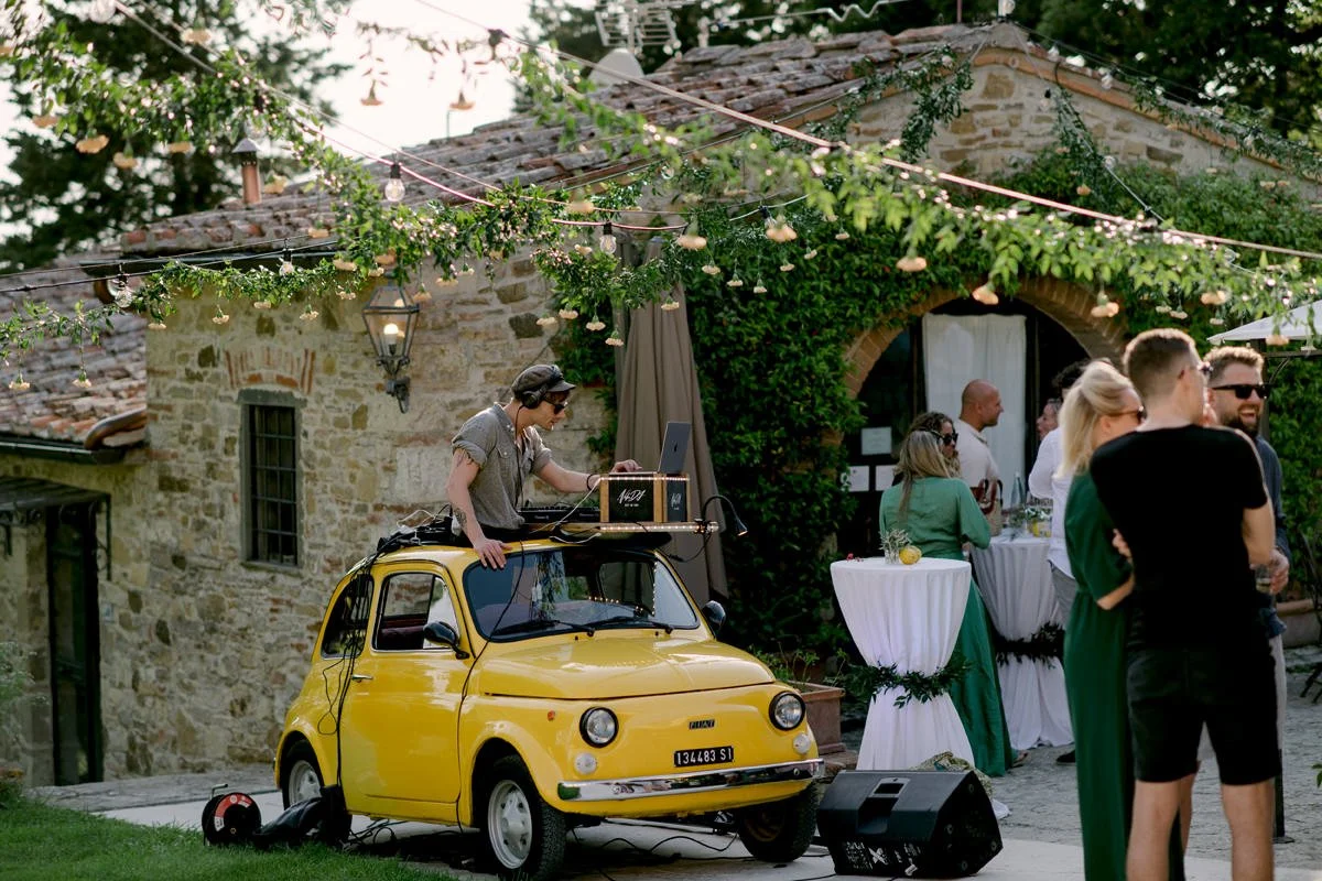 DJ playing music from a Fiat 500 during the welcome day party at Le Filigare wedding venue in Tuscany.
