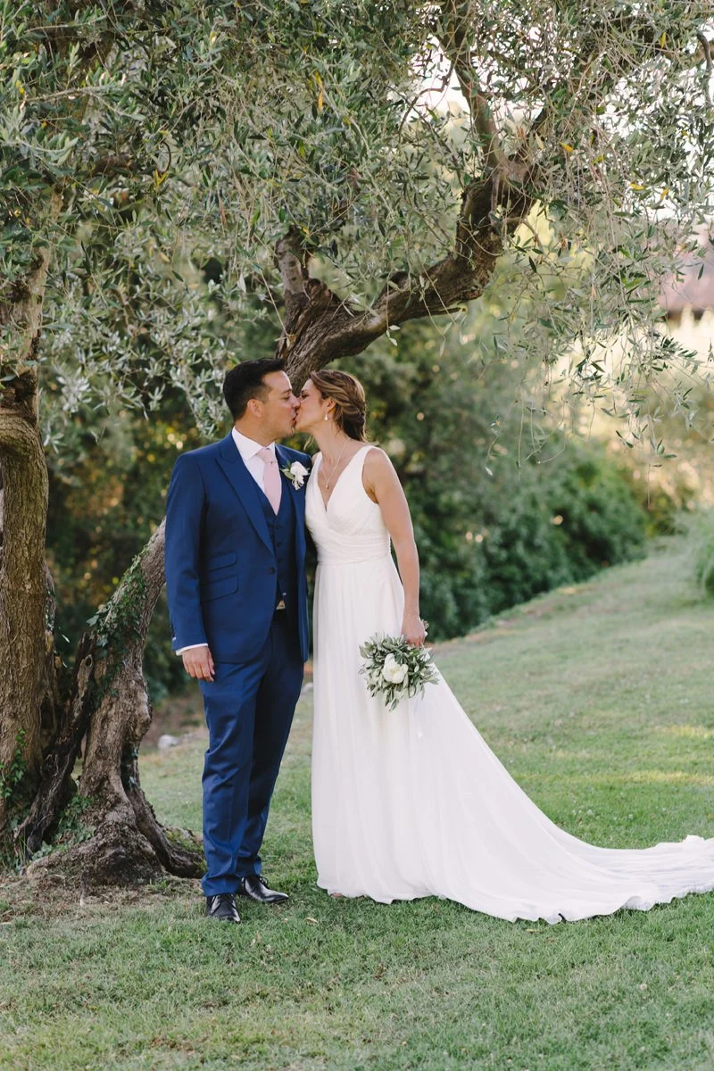 Wedding couple kissing among olive trees at Villa Artimino wedding venue in Tuscany.
